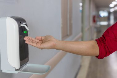 Ellerini otomatik alkol kutusunun altına koy. Enfeksiyon ve konuksever konsept. Hastalık virüsünü mikroplara karşı koru ve kamuya açık alanda temizle.. 