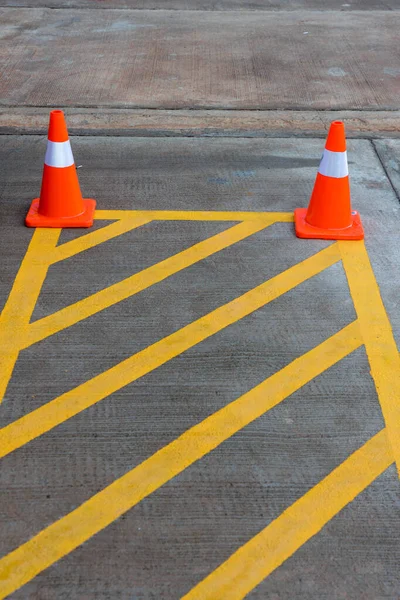 Parking lot with traffic cone on street used warning sign on road. Traffic warning cone in row to separate route in parking area. Vacant parking lot with traffic cone on street in the park.