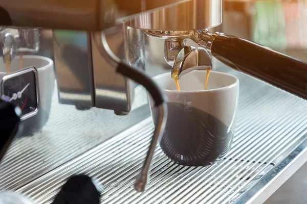 Coffee extraction from professional coffee machine. coffee machine preparing fresh coffee and pouring into cups at restaurant, bar or pub. Espresso shot from machine.