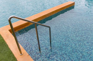 Yüzme havuzuna inmek için merdiven paslanmaz tırabzanlar. Tırabzanlı yüzme havuzu. Yüzme havuzu merdiveni. Yatay çekim.