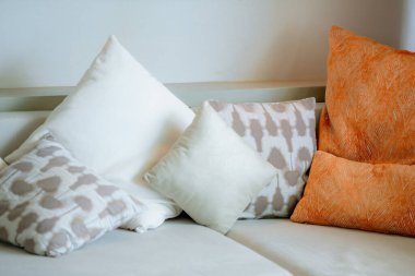 Kanepede yastık ve oturma odasının içinde sandalye süsü. Oturma odasındaki lüks koltukta yastıklar. Odasında renkli yastıklar olan kanepe.