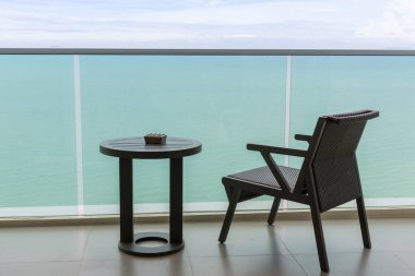 Açık balkonu ve denizi olan masa ve sandalye. Balkon deniz manzaralı sandalye ve masa. Okyanus manzaralı balkon otel odasındaki masalı sandalye..