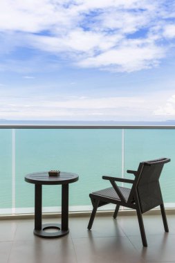 Açık balkonu ve denizi olan masa ve sandalye. Balkon deniz manzaralı sandalye ve masa. Okyanus manzaralı balkon otel odasındaki masalı sandalye..
