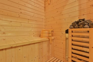 Sauna odasında otur. Taş ısıtıcılı boş ahşap buhar odası. Sağlıklı olmak için sauna odası. Sauna odası ve geleneksel sauna aksesuarları. Sağlıklı ve spa tarzı..