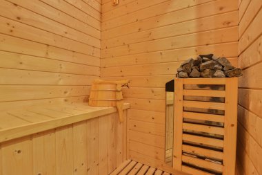Sauna odasında otur. Taş ısıtıcılı boş ahşap buhar odası. Sağlıklı olmak için sauna odası. Sauna odası ve geleneksel sauna aksesuarları. Sağlıklı ve spa tarzı..