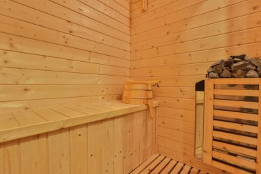 Sauna odasında otur. Taş ısıtıcılı boş ahşap buhar odası. Sağlıklı olmak için sauna odası. Sauna odası ve geleneksel sauna aksesuarları. Sağlıklı ve spa tarzı..