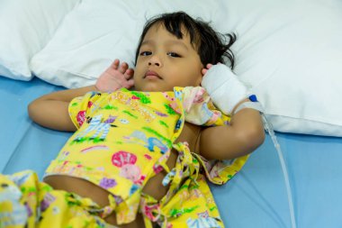 Küçük bir çocuk hastane yatağında hastanın eline damar içi tüp takıyor. Bebek hasta ve hastanede hasta yatağında uyuyor. Damardan serum fizyolojik ya da bebeğin eline damlat.. 