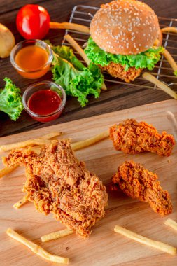 Tahta arka planda ateş edilmiş tavuk, tavuk nugget ve baharatlı bagetler. Bir çift kızarmış tavuk. Dekorasyonda kızarmış tavuk ve ahşap masa arkasında malzeme.