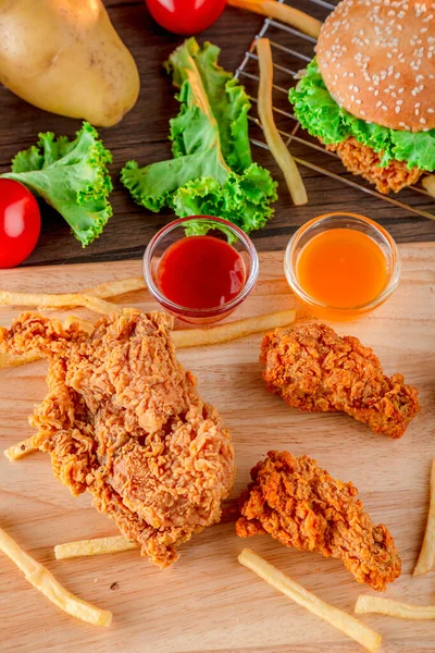 Fired chicken and chicken nuggets and spicy drumsticks on wooden background. Set of fired crispy chicken. Crispy fried chicken in  decoration with ingredient on  wooden table background