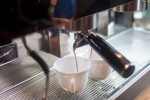 Coffee extraction from professional coffee machine. coffee machine preparing fresh coffee and pouring into cups at restaurant, bar or pub. Espresso shot from machine.