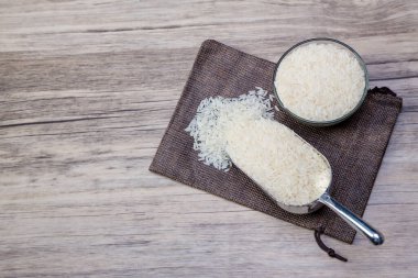 Pirinç çuvalına konulan pilav. Beyaz pirinç ya da Tayland yasemin pilavı ahşap masa arkasında ahşap kase içinde.