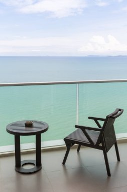 Açık balkonu ve denizi olan masa ve sandalye. Balkon deniz manzaralı sandalye ve masa. Okyanus manzaralı balkon otel odasındaki masalı sandalye..