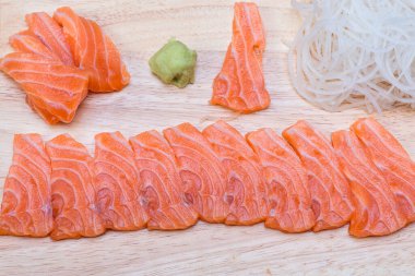 Dilimlenmiş somon fileto. Çiğ somon balığı. Japon mutfağı. Tahta kesme tahtasında lezzetli taze somon balığı filetosu dilimleri. Somon fileto kırmızı balık dilimleri..