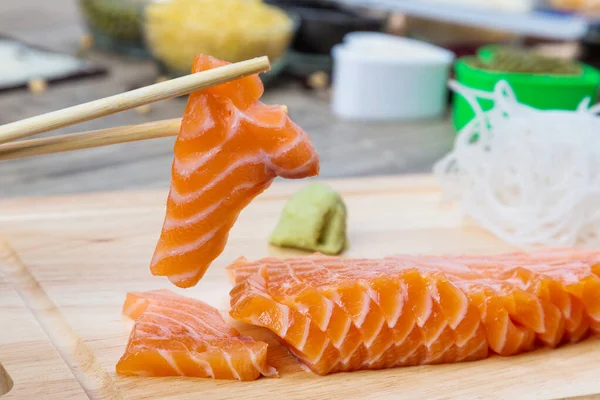 Salmon Fillet Sliced. Salmon raw sashimi. Japanese cuisine. Delicious fresh slices of salmon fish fillet on Wooden cutting board. Salmon fillet red fish slices.