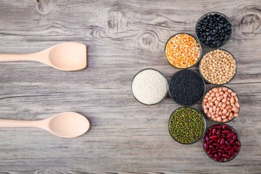 Tahta arka planda tahıl tohumları. Tam tahıl ve fasulye. Mısır gevreği ve fasulye. Sağlıklı beslenmek için farklı kuru baklagiller. Fıstık, kara fasulye, kırmızı fasulye. Yeşil fasulye, soya fasulyesi, susam.