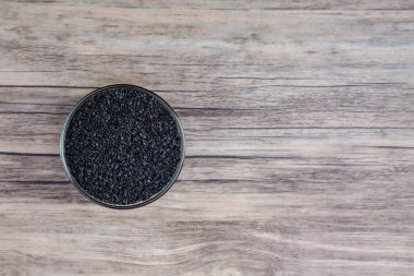 Kasede siyah susam. Tabakta kurumuş siyah susam tohumları var..