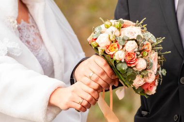 Gelin ve damat bankta parlak giysiler içinde.