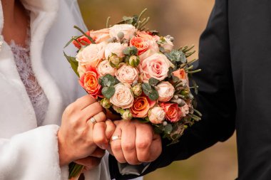 Gelin ve damat bankta parlak giysiler içinde.