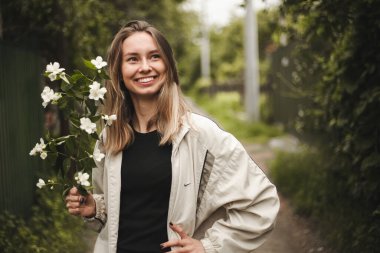 Doğanın arka planında güzel sarışın bir kızın portresi. Güzel gülüşü olan mutlu bir kız elinde bir buket çiçek tutuyor. Bahar fotoğrafı.