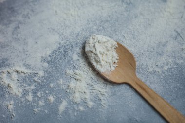 Gri arka planda un olan tahta kaşık. Yemek pişirme süreci, bir yazı için yer