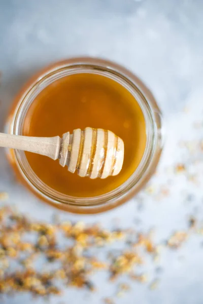 Honey flows from a honey spoon into a jar. Sweet Honey.