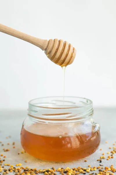 Honey flows from a honey spoon into a jar. Sweet Honey.