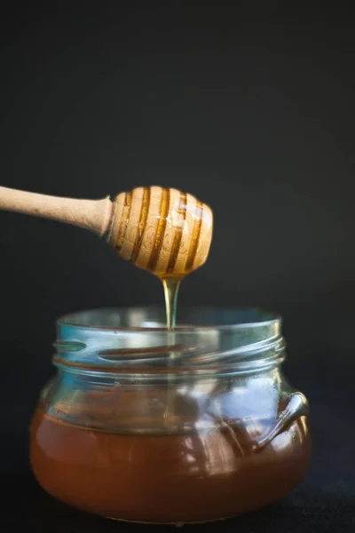 Honey flows from a honey spoon into a jar. Sweet Honey.