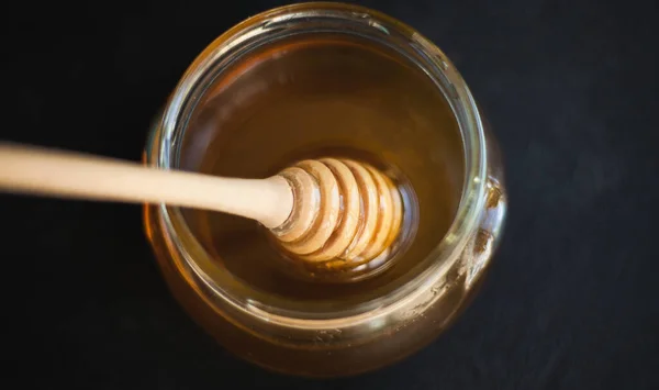 Honey flows from a honey spoon into a jar. Sweet Honey.