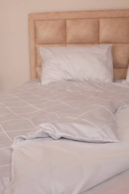 Yapılmamış boş yatak. Beyaz çarşaflar. Ev konforu