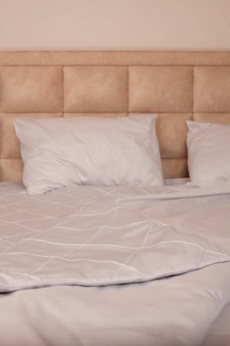 Yapılmamış boş yatak. Beyaz çarşaflar. Ev konforu