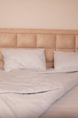 Yapılmamış boş yatak. Beyaz çarşaflar. Ev konforu