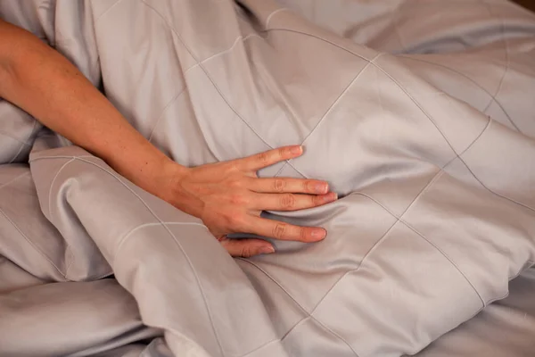 Gri bir yatağın arka planında bir kadın eli. Yakın plan fotoğraf.
