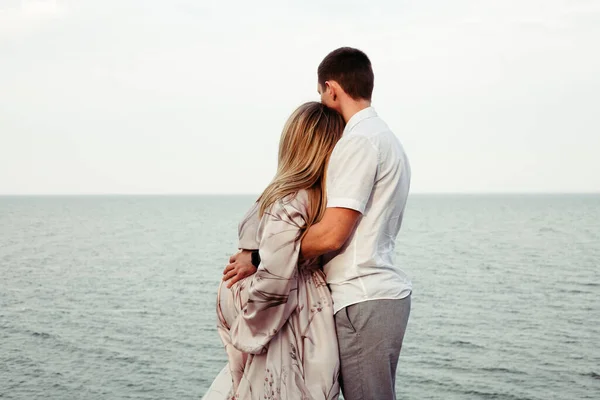 一位孕妇和她的丈夫在大海的背景下拥抱在一起 登记地点 — 图库照片