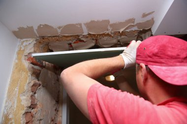 Duvarlar ve derleme doldurma ve bir oda yenileme sırasında alçı panoları yapıştırma.