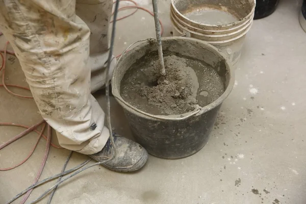 The construction worker mixes tile adhesive together with the water in the correct proportions.