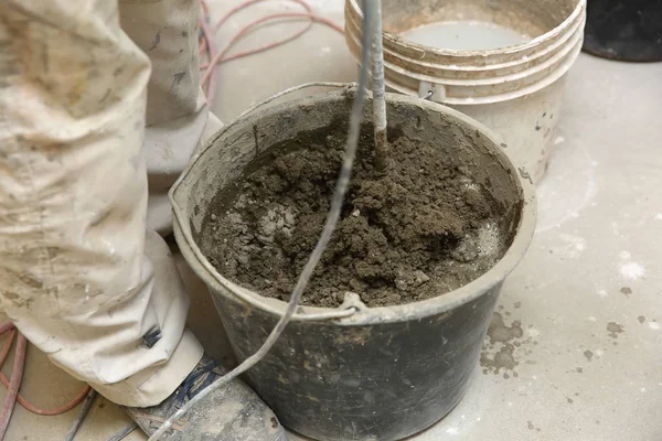 The construction worker mixes tile adhesive together with the water in the correct proportions.