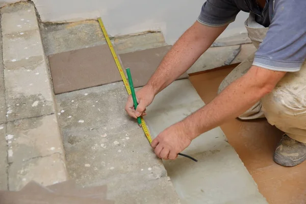 ビルダーは階段井戸のセラミック タイルの敷設を手配するスコップで床を測定します — ストック写真
