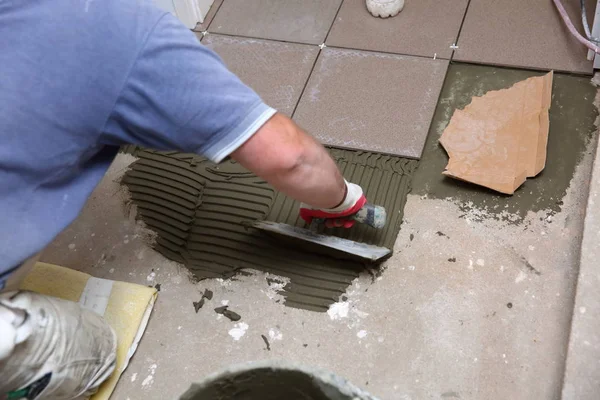 봉사자들은 도구를 사용하여 시멘트 접착제를 사용하여 층계의 표면을 고르게 퍼뜨린다 — 스톡 사진