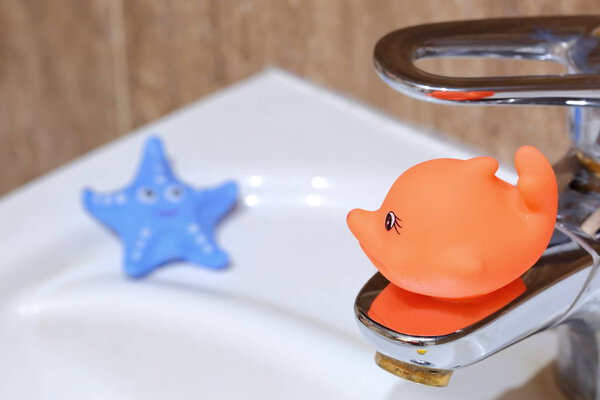 The red fish decorates the bathroom while sitting near the bathroom sink.