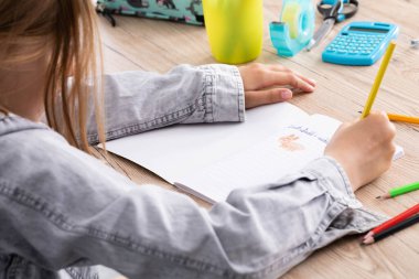 Dersteki kıza bir oyuncak ayı çizme görevi verildi. Genç liseli kız okul defterine pastel boyalarla resim çiziyor..