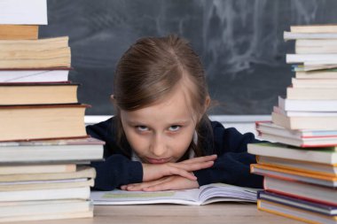 Genç liseli kız. Öğrenmek için kitap, sözlük ve ansiklopedi yığını gerekli.