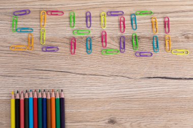 Renkli ofis ataçları. Yazı okulu. Renkli kalem boyaları. Ahşap okul bankı..