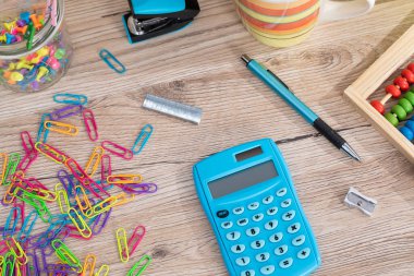 Masanın üstünde ahşap bir abaküs ve elektronik mavi bir hesap makinesi var..