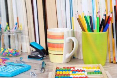 Masanın üstünde ahşap bir abaküs ve elektronik mavi bir hesap makinesi var..