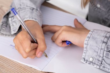 Liseli kız görevi çözer. Kız kalemle bir deftere yazıyor. İlkokul.