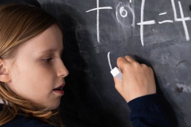 Tahtaya tebeşirle yazı yazıyor. Matematik problemi. Tahtadaki kız..
