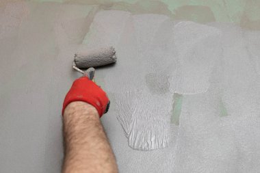 Tecrübeli bir inşaat işçisinin duvarda boya silindiri ile rutubetli yalıtım uygulaması..