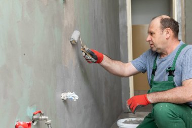 Banyo tadilatı. İnşaat işçisi. Mineral nem yalıtımı. İş sırasında..