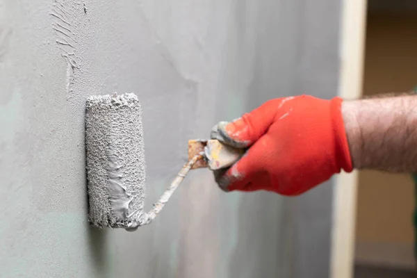 一名经验丰富的建筑工人在墙壁上涂上带油漆辊的保温材料的特写镜头 — 图库照片