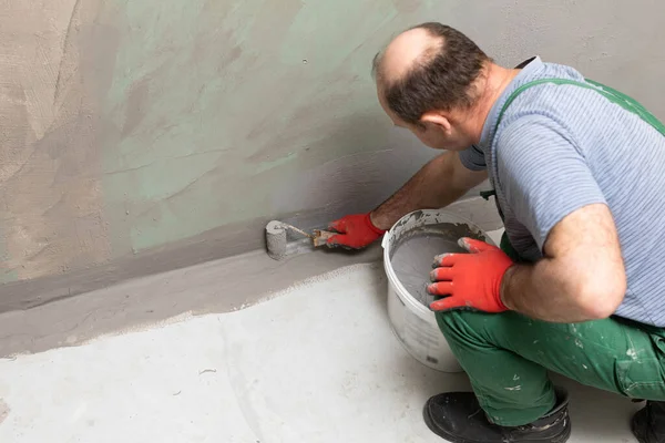 Bathroom renovation. Construction worker. Mineral moisture insulation. During work.